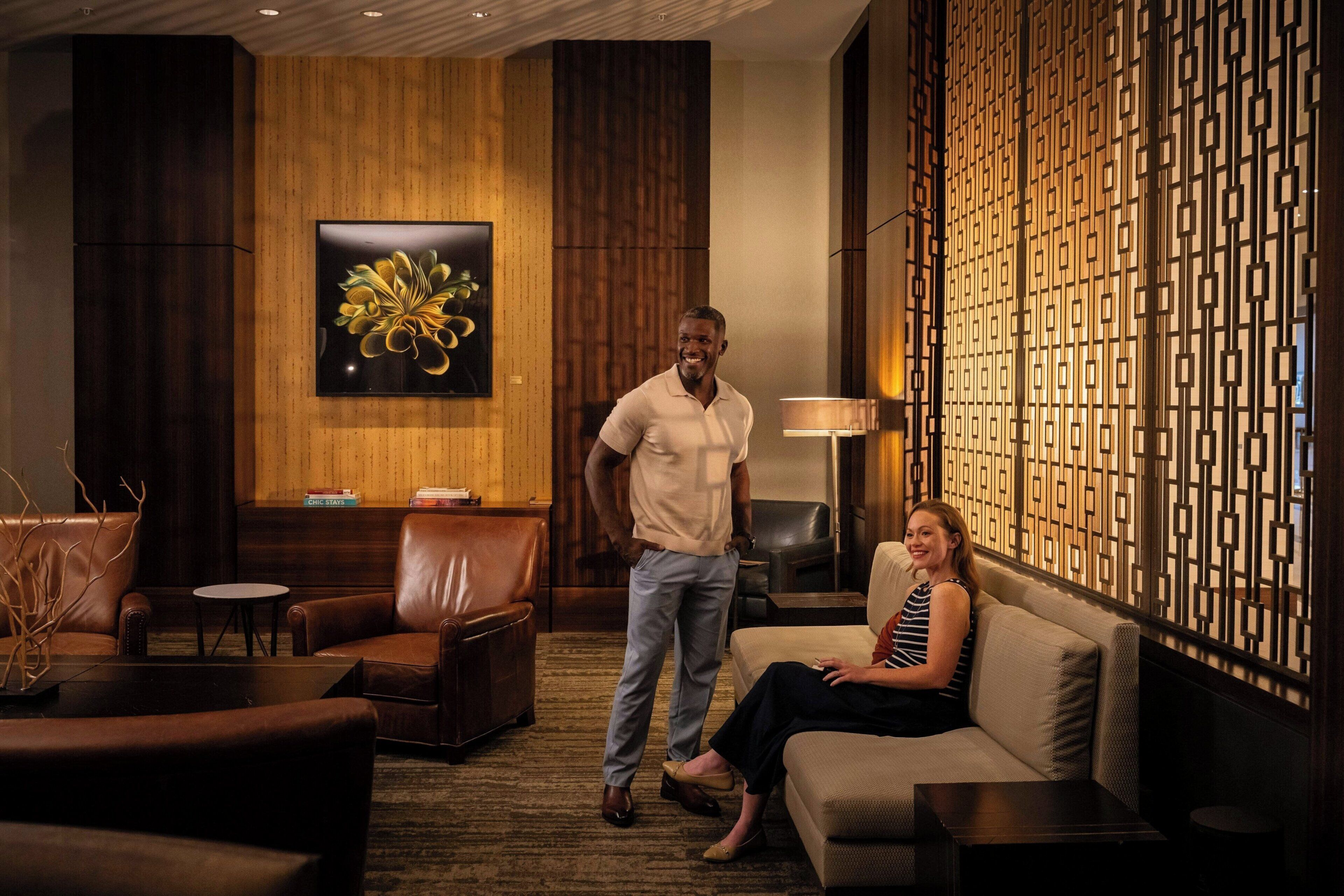 A modern hotel lobby with leather seating, a large abstract painting, and a decorative wall panel.
