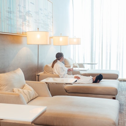 A modern hotel room with a sofa, a small table, and a lamp.