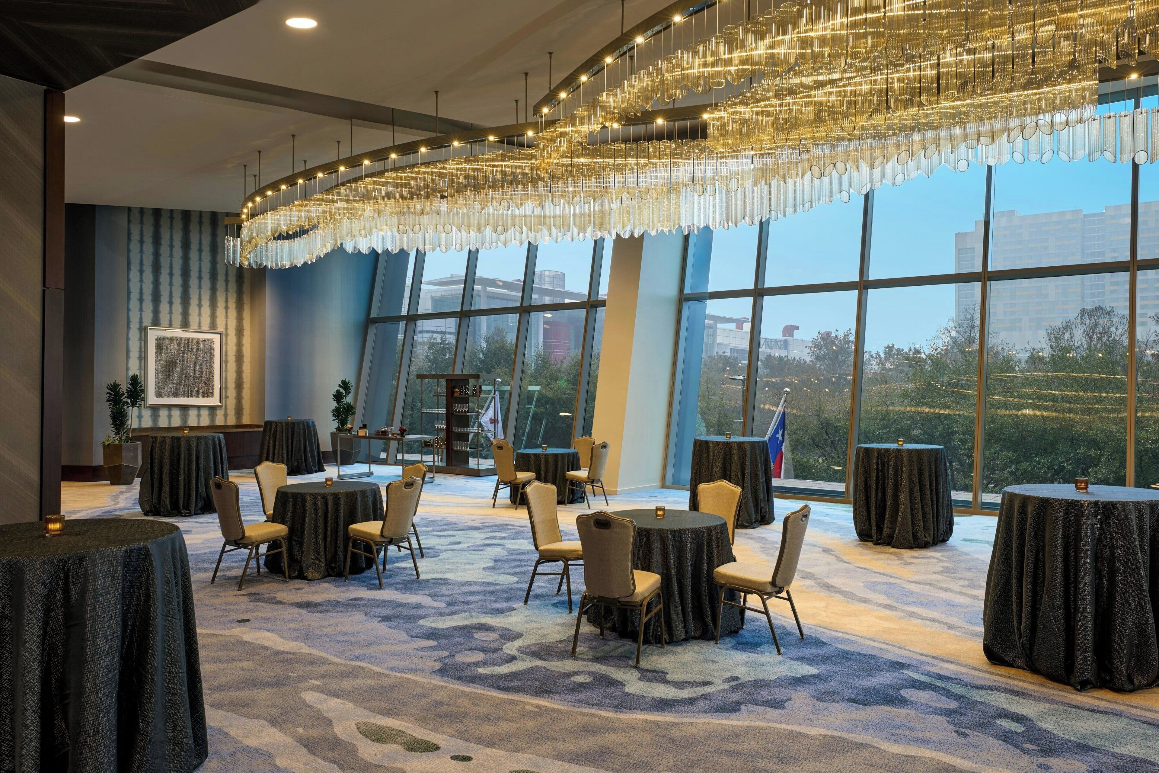 A conference room with round tables, chairs, and a large chandelier.