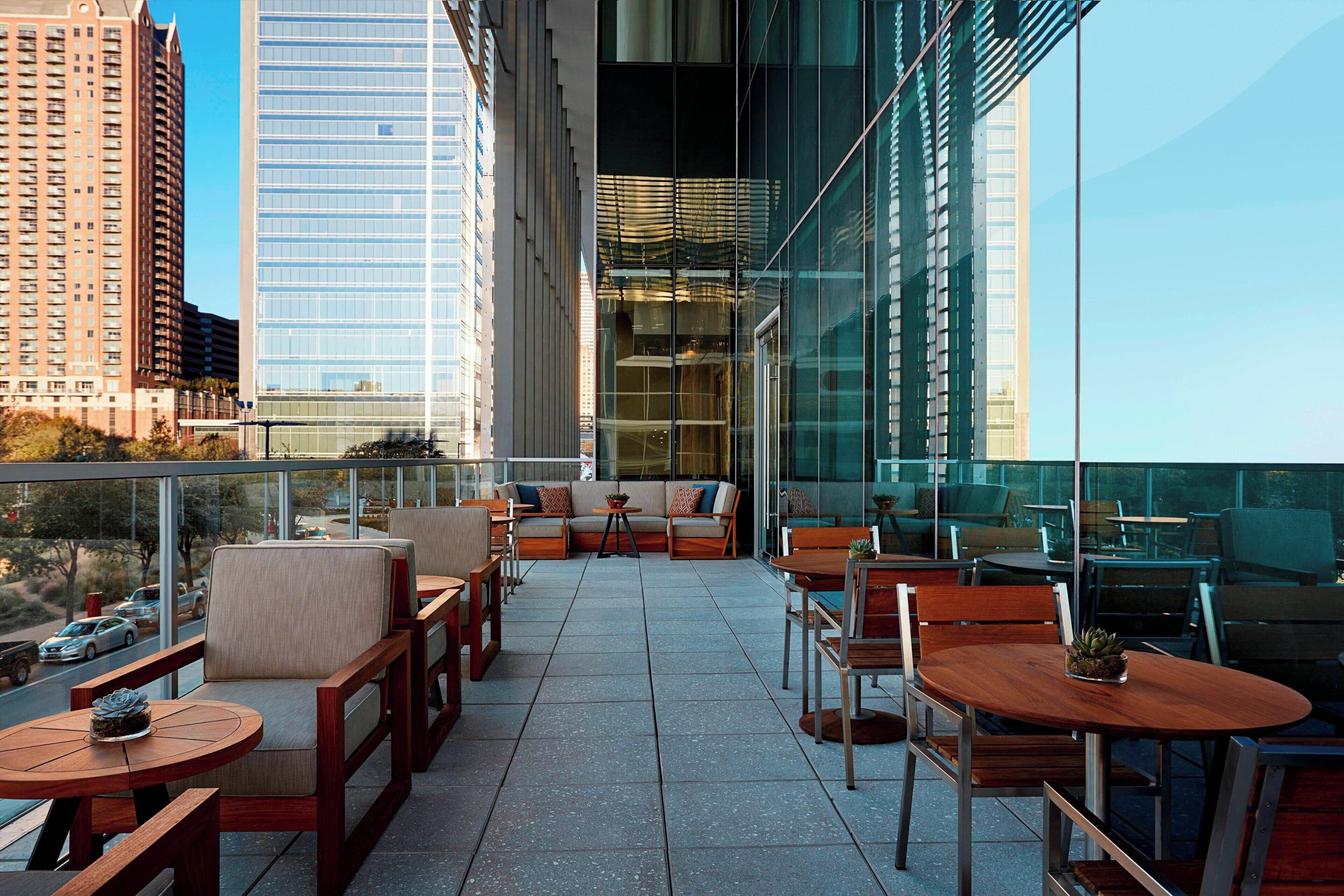 Una terraza en la azotea con mobiliario exterior, vistas a la ciudad y arquitectura moderna.