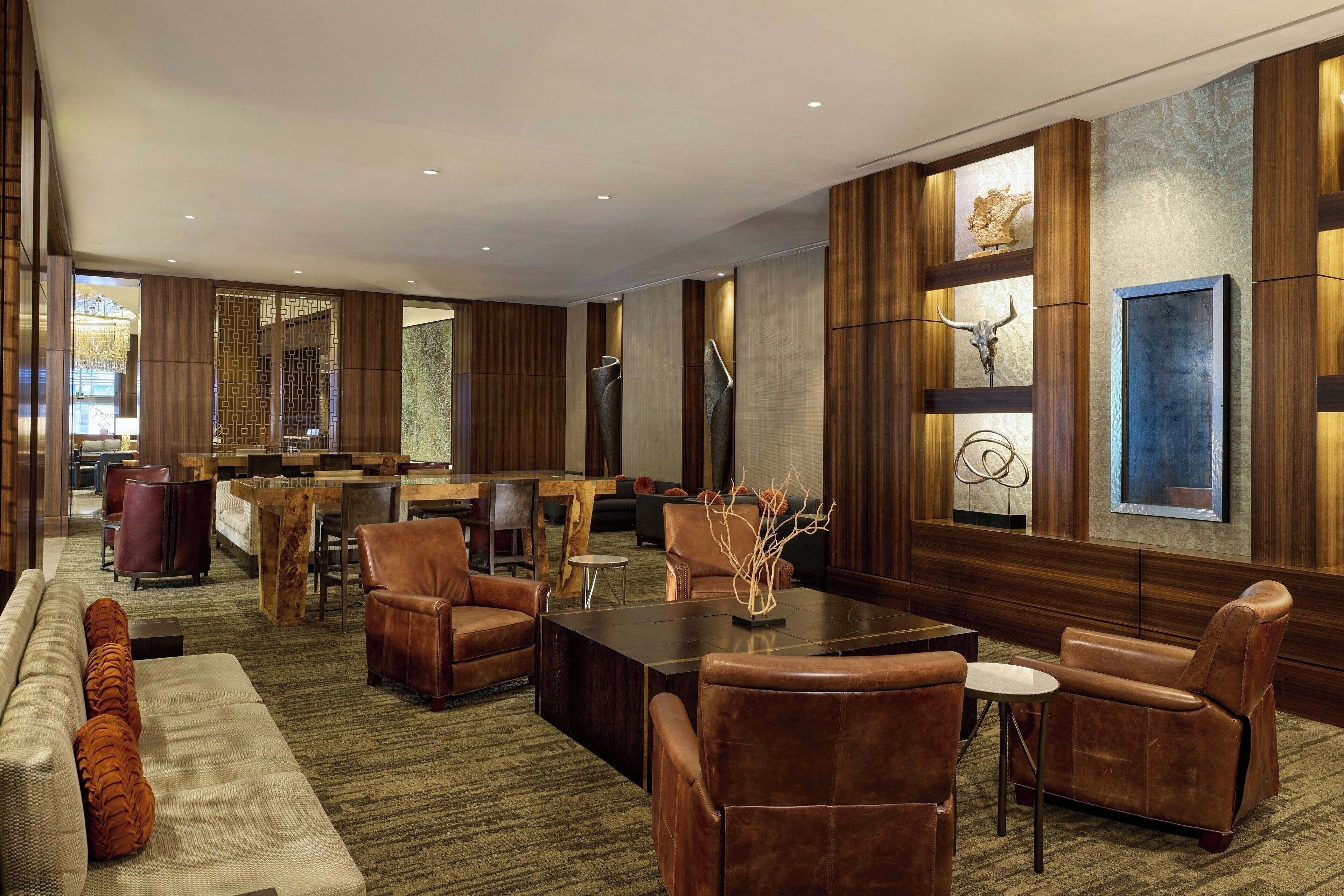 A spacious lobby with leather sofas, a wooden reception desk, and a dining area.