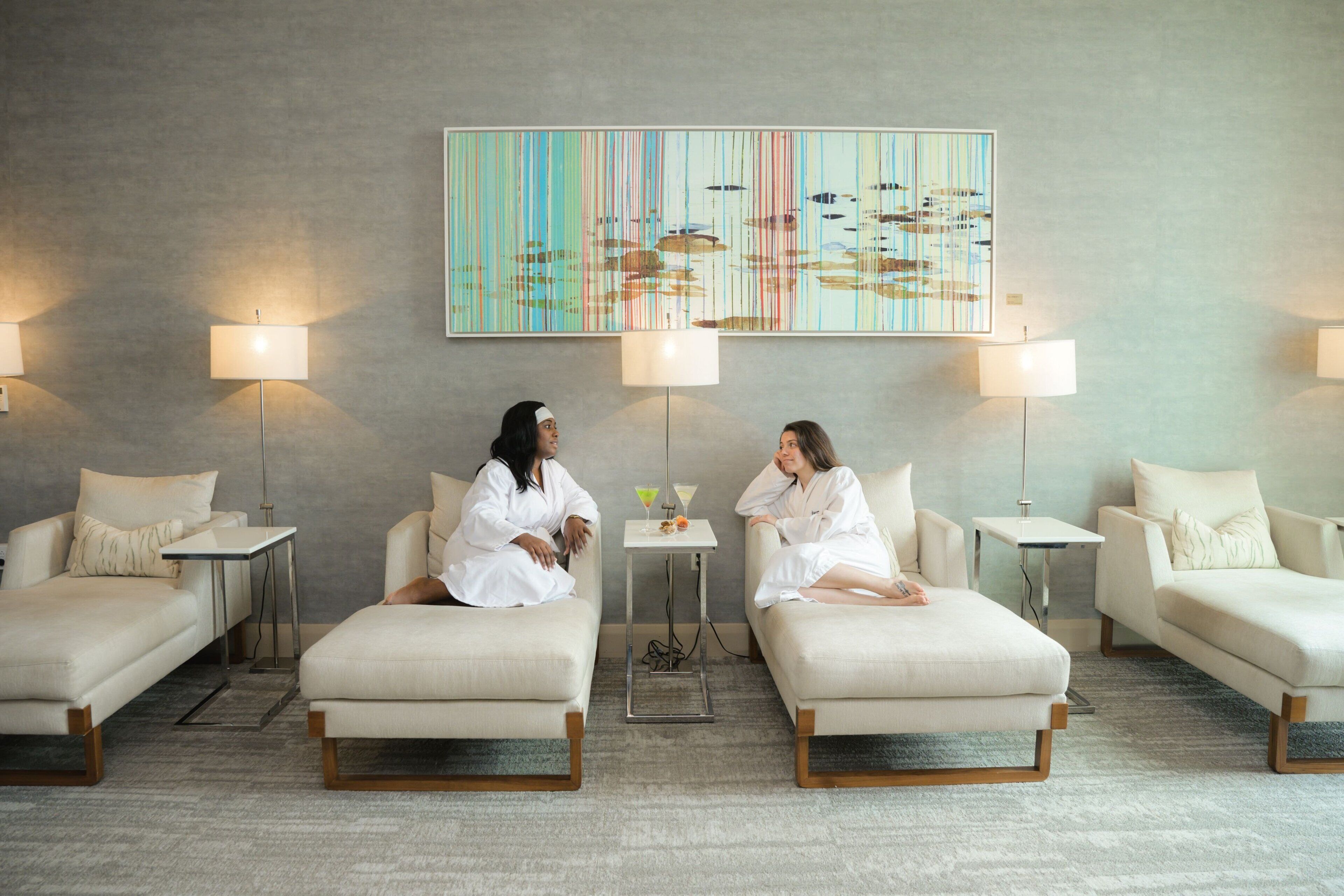 A hotel room with two sofas, a small table, and a painting on the wall.