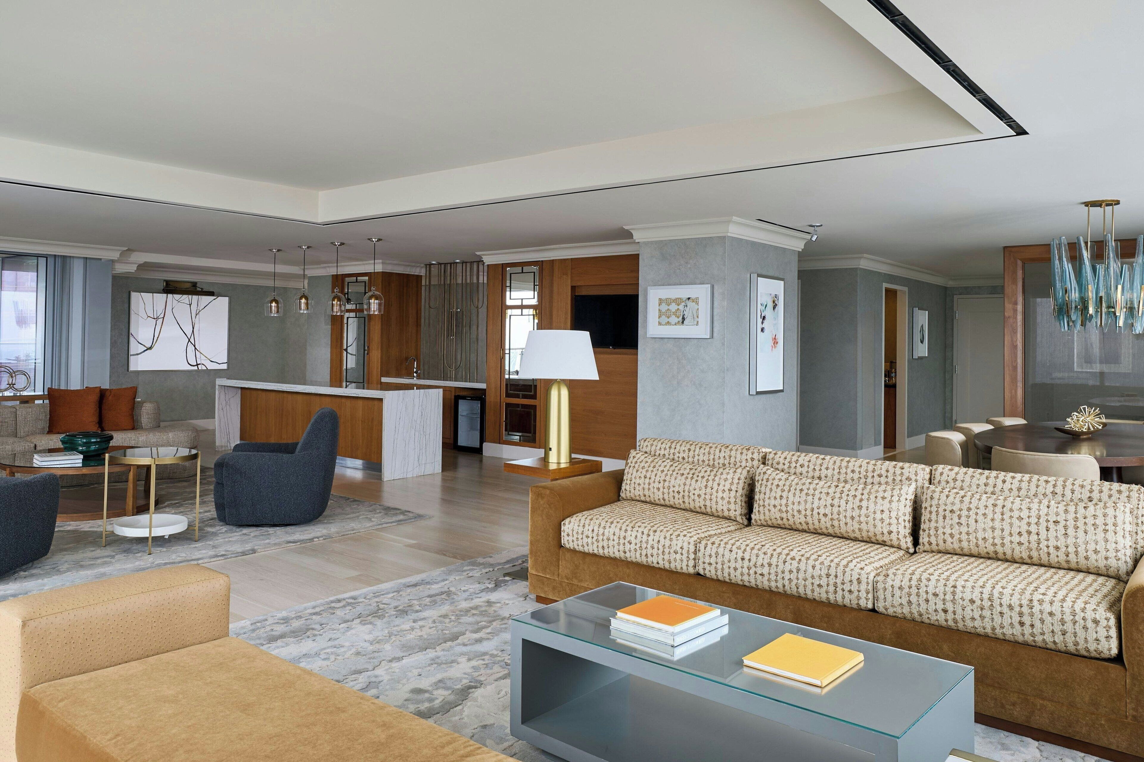 A modern living room with a sofa, coffee table, and a dining area with a chandelier.