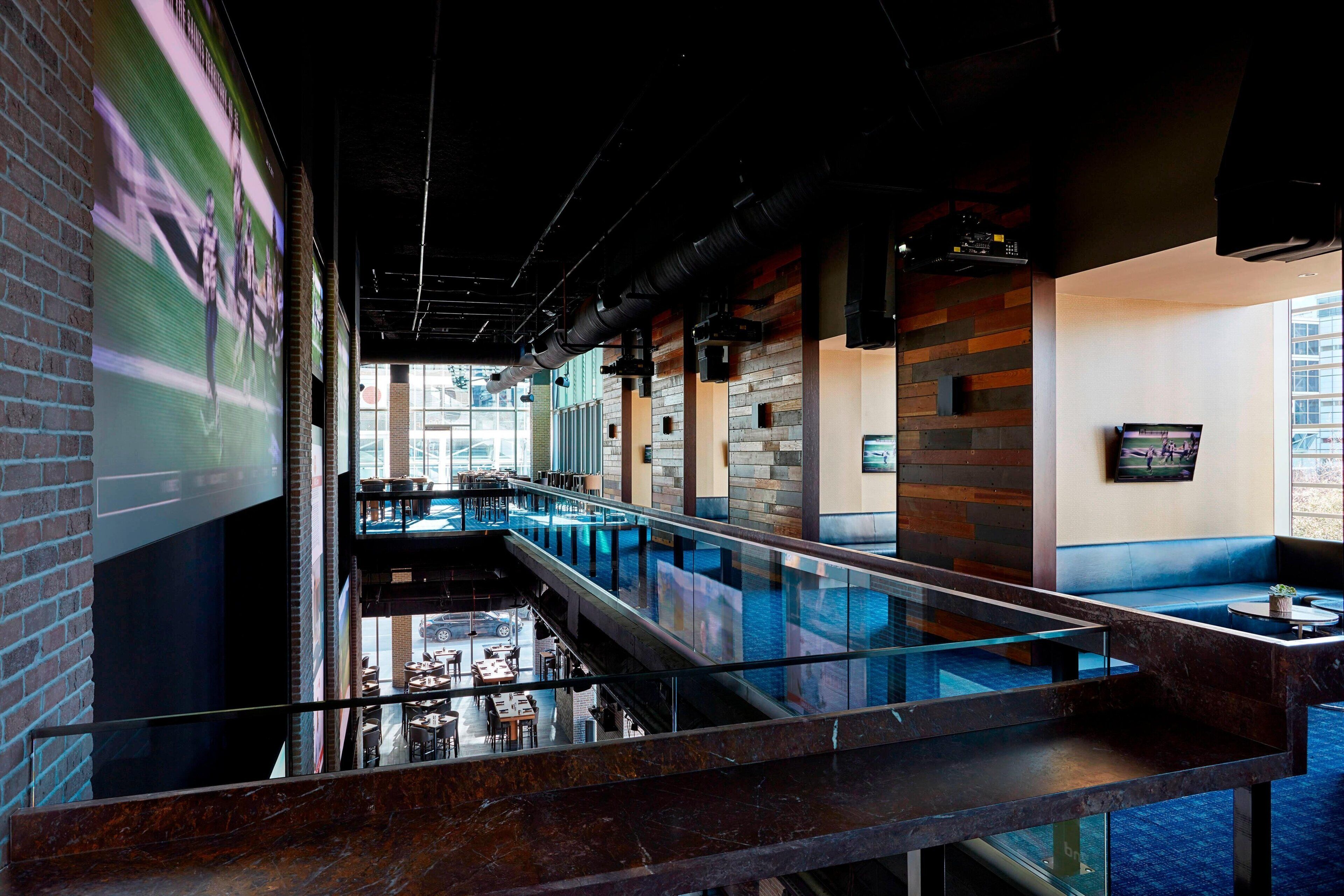 A multi-level interior with a glass barrier, wooden panel walls, and a view of the street below.