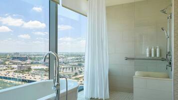 Uma casa de banho moderna com banheira, chuveiro e vista para a cidade.