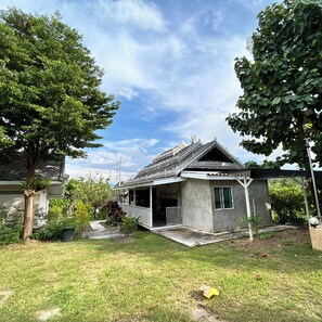A traditional house with a tiled roof, a porch, and a garden with trees and grass. - Por Ar Yor Resort (Pai)