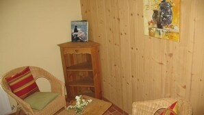 Une pièce comprenant deux fauteuils en osier, une petite table en bois et un tableau accroché au mur.