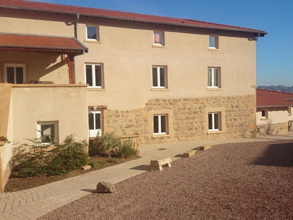 Un edificio de varios pisos con fachada de piedra, numerosas ventanas y camino de entrada de grava.