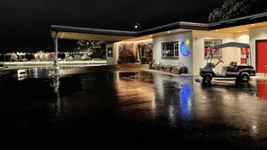 A well-lit building with a covered outdoor area, a golf cart, and a neon sign. - The Sapphire Motel (Bozeman)