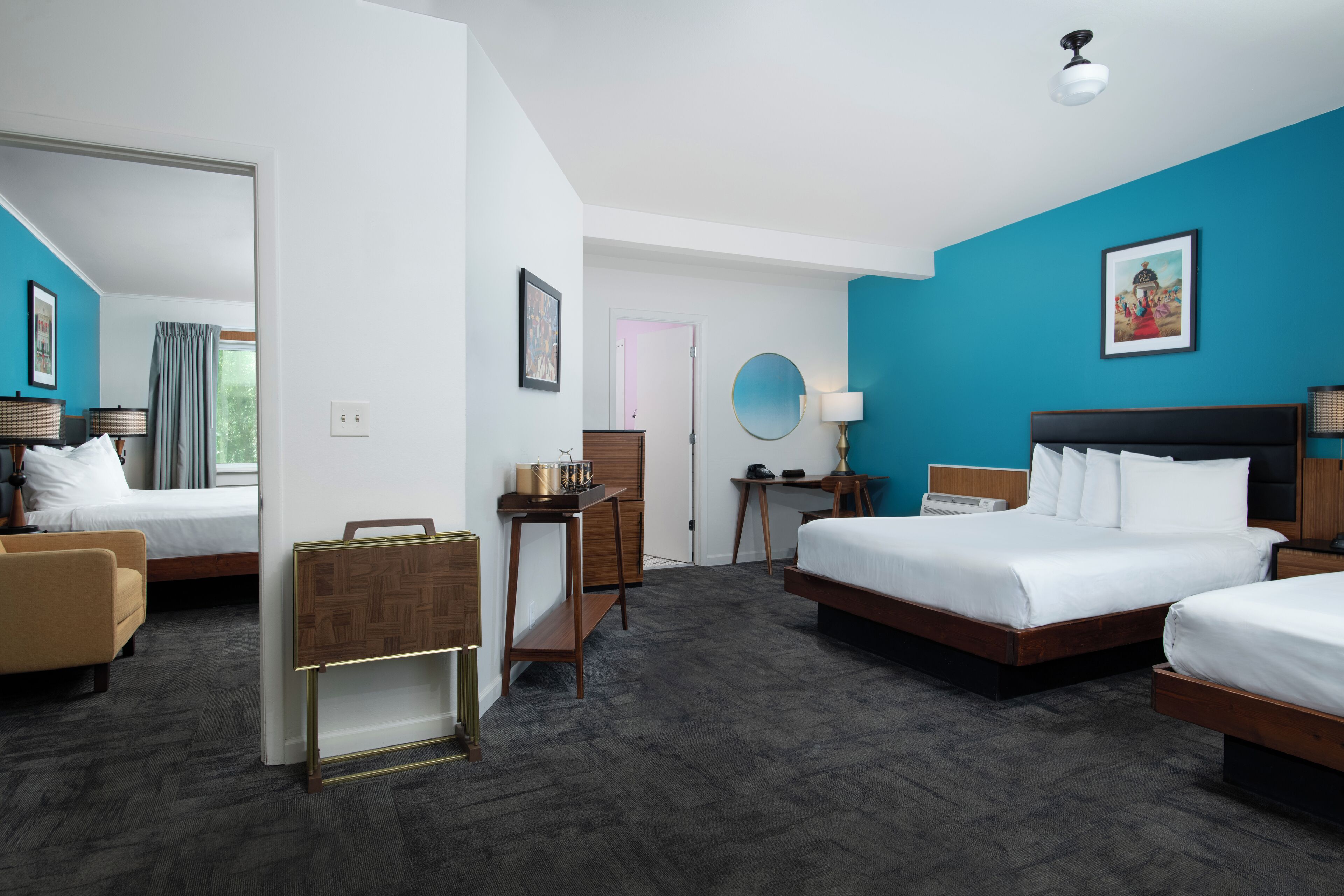 Hotelkamer met twee bedden, een bureau, een stoel, een kledingkast en een badkamer die door een geopende deur zichtbaar is.