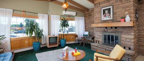 A cozy living room with a fireplace, comfortable seating, and large windows.