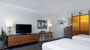 A hotel room with a bed, a desk with a chair, a television, and a potted plant. - The Sapphire Motel (Bozeman)
