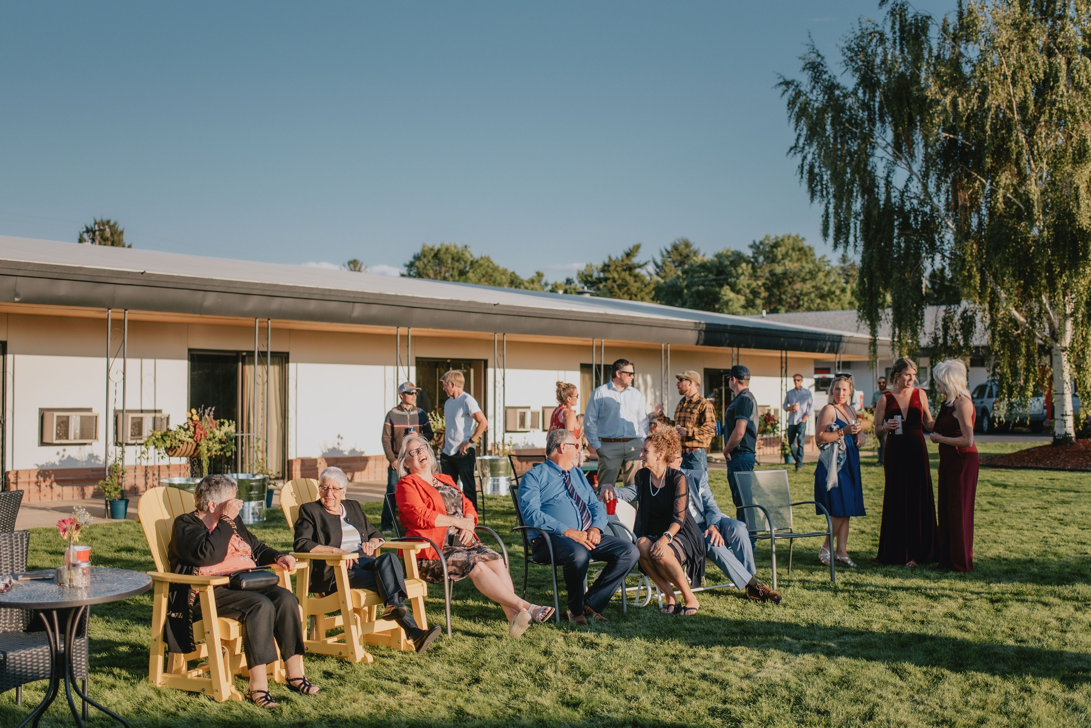 A group of people seated on lawn chairs in an outdoor setting with a building in the background.