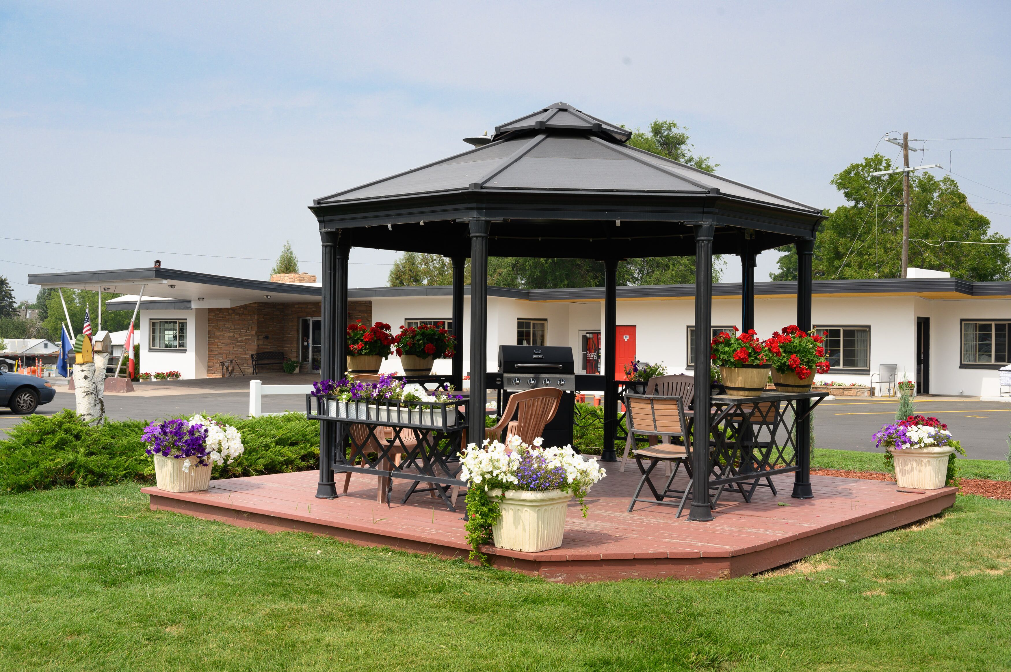 Un belvédère doté d’un toit, entouré d’une terrasse en briques et aménagé avec des tables et des chaises.