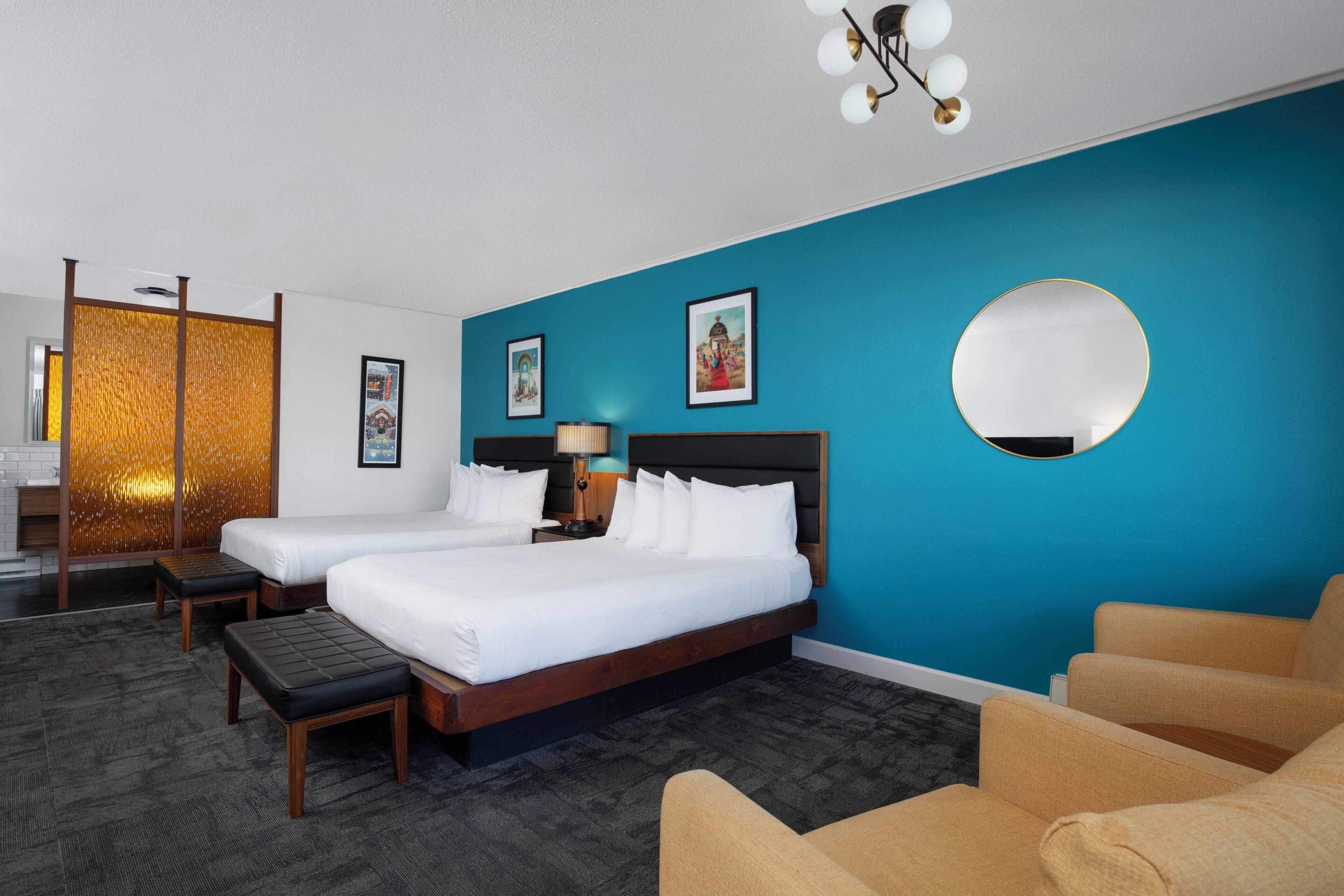 Een hotelkamer met twee bedden, een ronde spiegel en een zithoek.