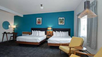 Une chambre d’hôtel avec deux lits, un bureau, une chaise et un luminaire suspendu.