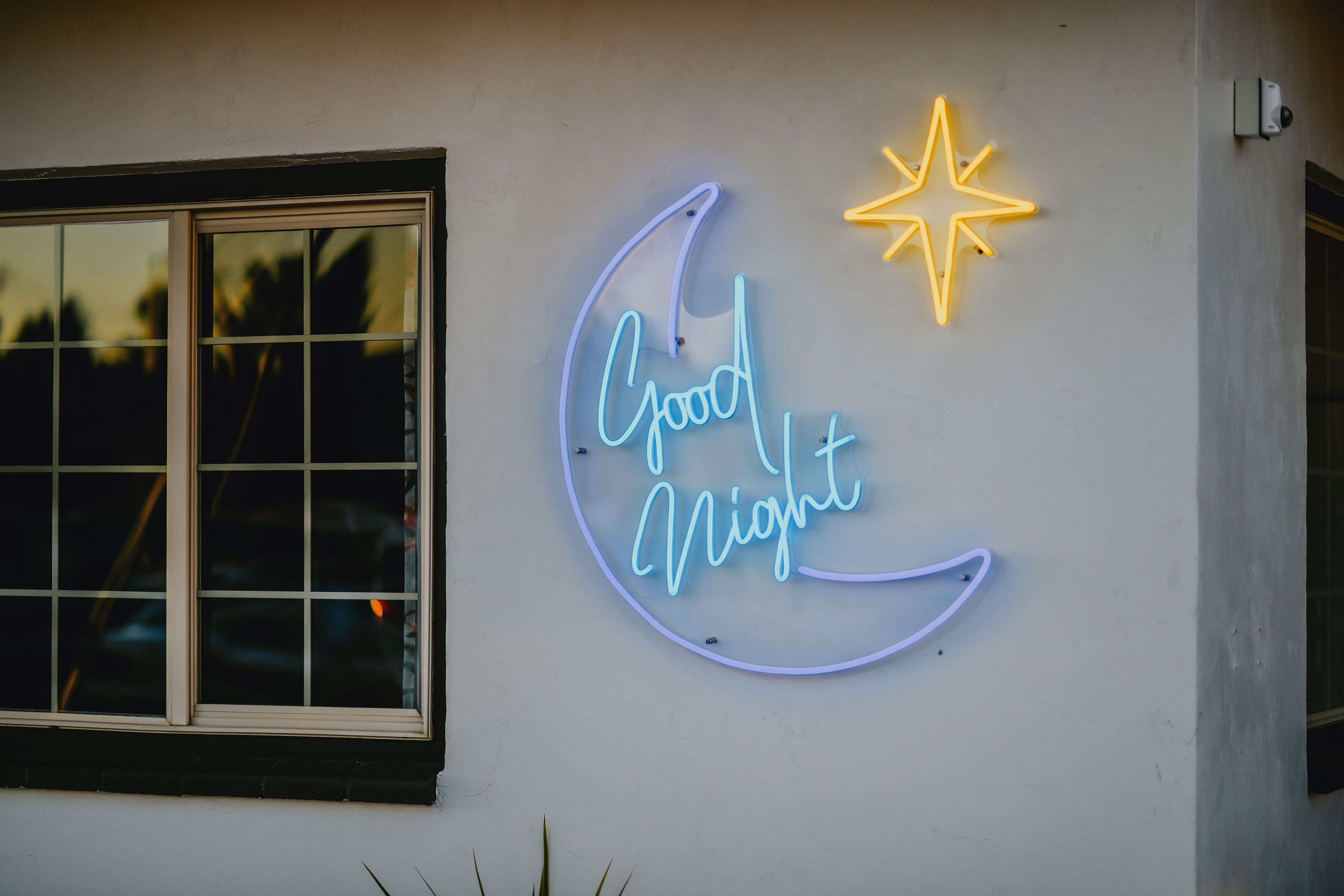 Une enseigne au néon sur le mur d’un immeuble, avec l’inscription « Bonne nuit » et une étoile au-dessus.