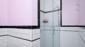 Une salle de bain moderne avec des murs carrelés en noir et blanc, une douche en verre et un mur d’accent rose.