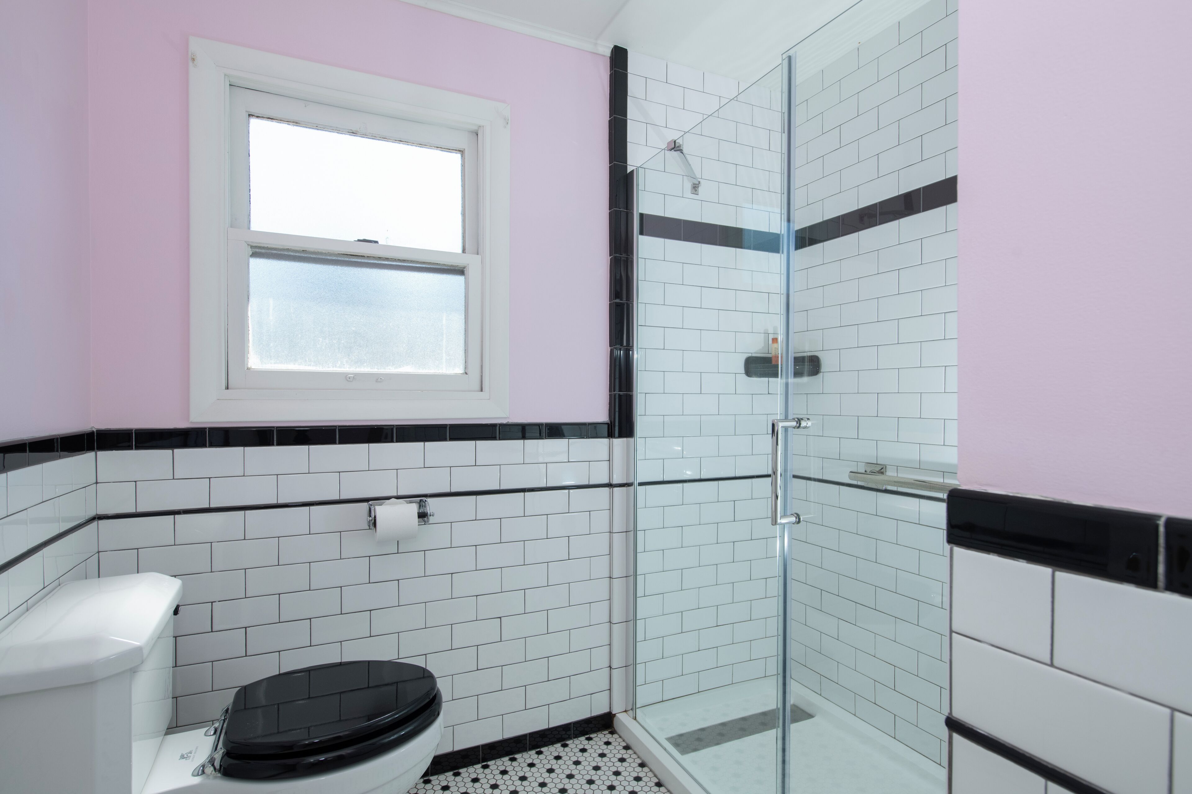 A bathroom with a toilet, a shower, and a window.