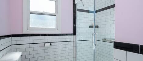A bathroom with a toilet, a shower, and a window.