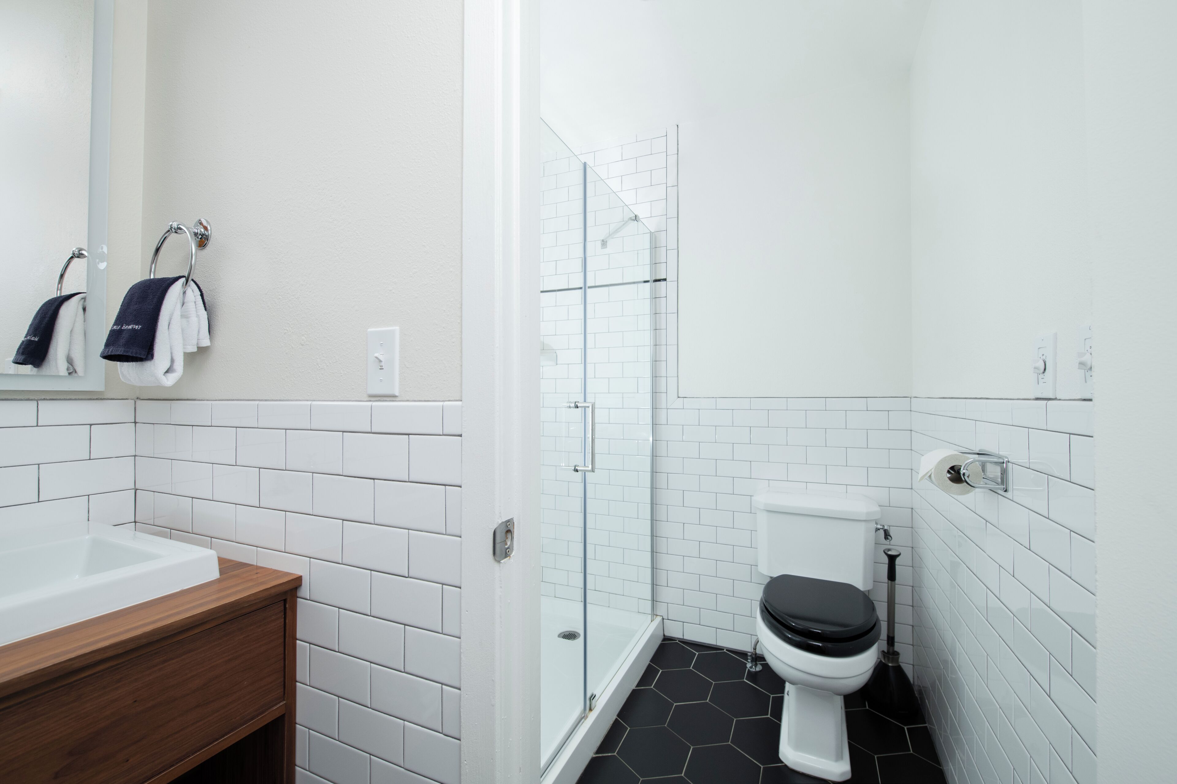 Une salle de bain moderne avec un lavabo blanc, un meuble-lavabo en bois, une cabine de douche en verre et des toilettes.