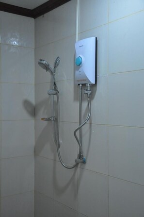 A wall-mounted shower unit with a control knob, a handheld showerhead, and a flexible hose.