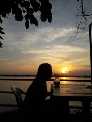 A person sitting at a table with a sunset view.