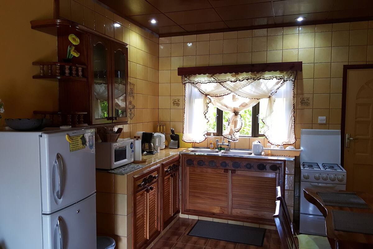 Eine kleine Küche mit Kühlschrank, Mikrowelle, Spüle und Herd.