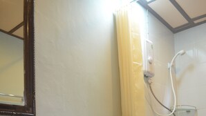 A bathroom with a glass bowl sink, a toilet, a shower with a yellow curtain, and a mirror on the wall. - Baan Aew Pai (Pai)