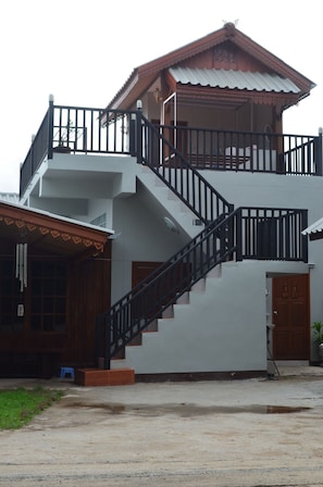 A two-story building with a staircase, a balcony, and a door.