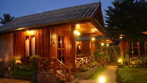 A wooden building with a porch and steps, surrounded by potted plants and a pathway. - Baan Aew Pai (Pai)