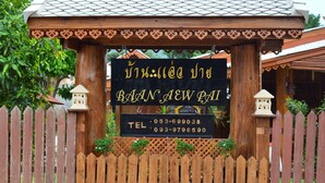 A wooden sign with Thai text and contact numbers for Baan New Bai. - Baan Aew Pai (Pai)