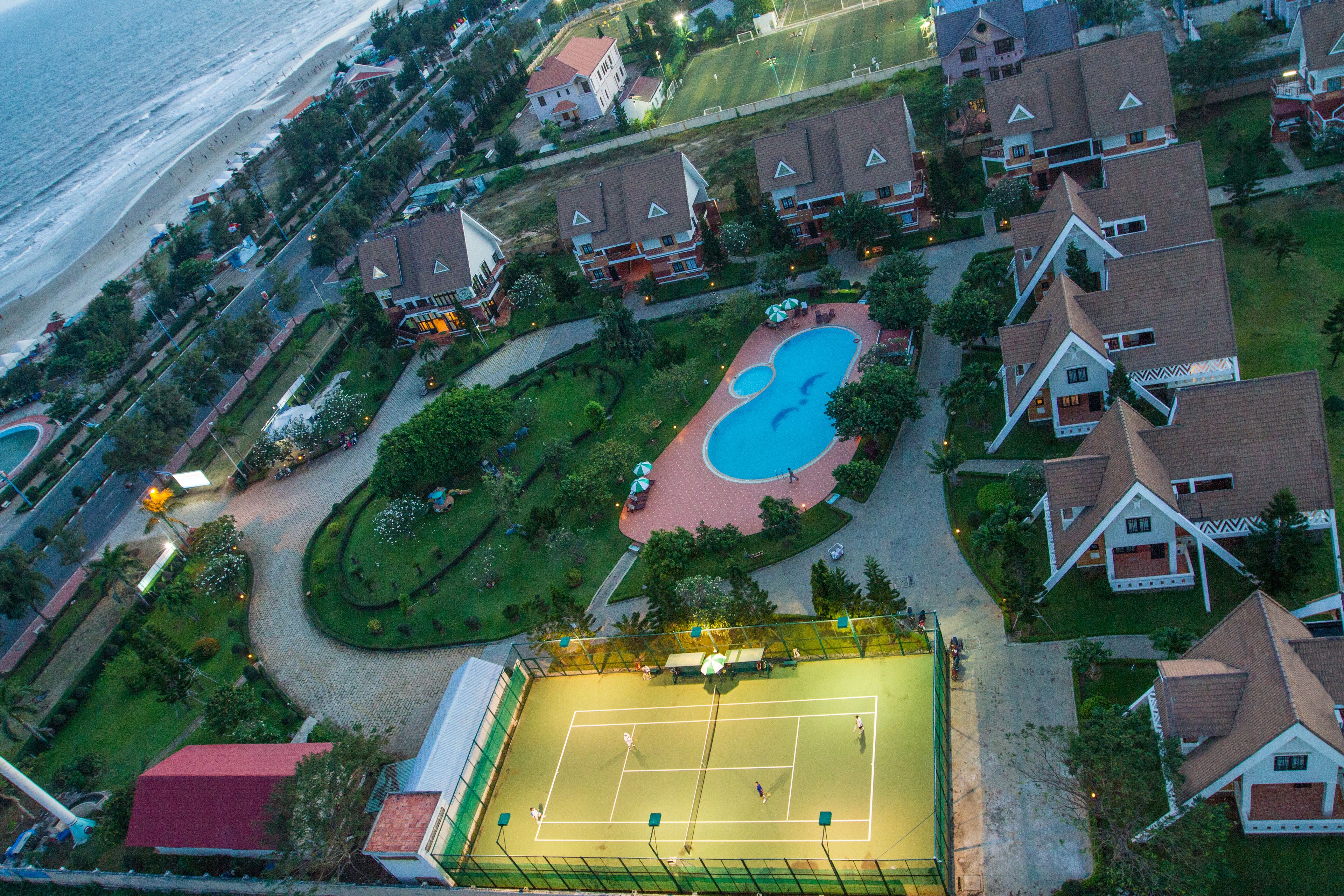 Vista aérea de una zona residencial con casas, una cancha de tenis y una piscina.