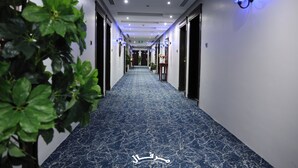 A hotel corridor with a blue marble floor, doors on both sides, and wall-mounted light fixtures. - Merfal Serviced Apartments-Royal (Riyadh)