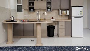 A modern kitchen with a central island, built-in microwave, and a refrigerator. - Merfal Serviced Apartments-Royal (Riyadh)