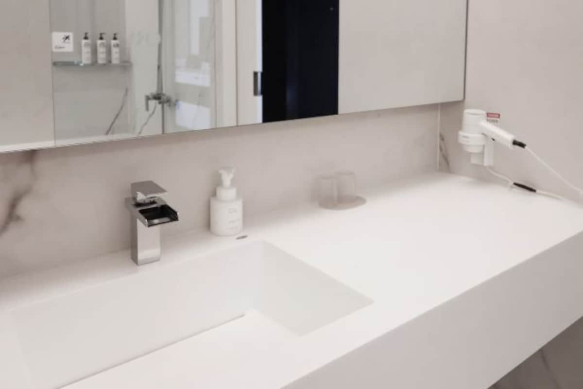 A modern bathroom with a white sink, a mirror, and a glass shower enclosure.