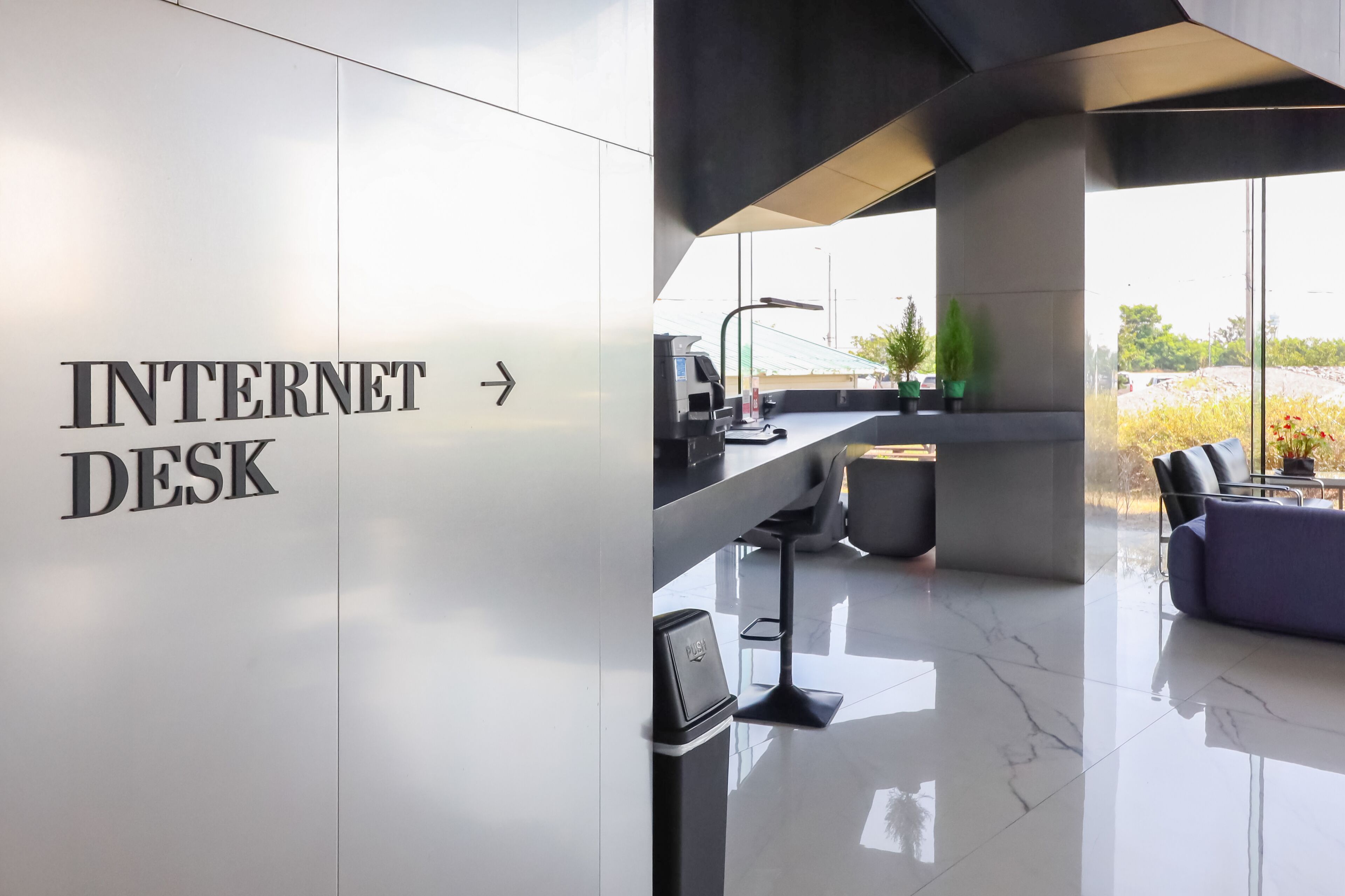 A modern interior with a sign for an Internet Desk, a sleek bar area, and a view through large windows.