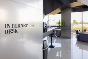 A modern interior with a sign for an Internet Desk, a sleek bar area, and a view through large windows.