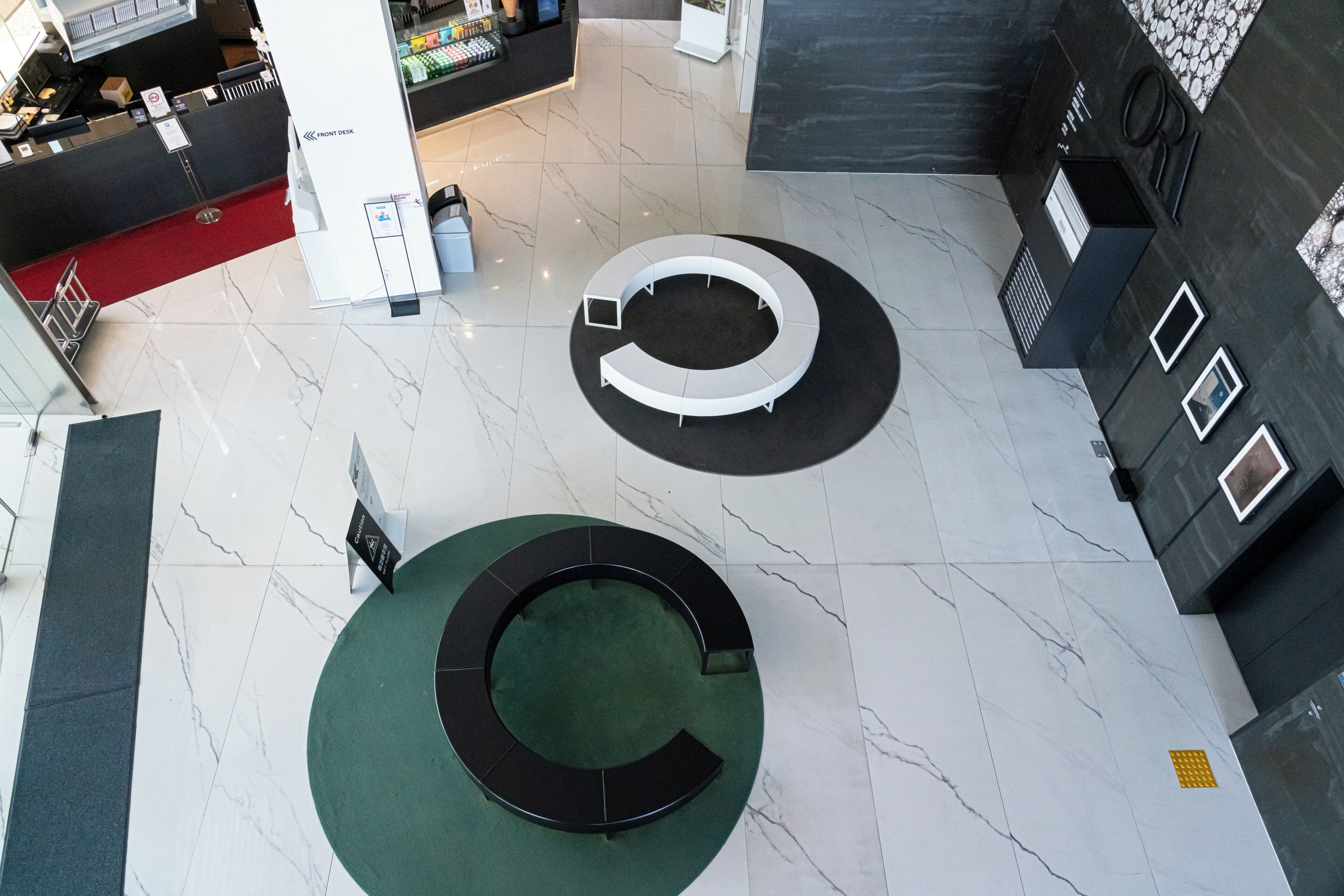 A modern lobby with a circular seating area, a reception desk, and a marble floor.