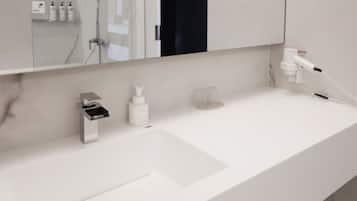 Un baño moderno con un lavamanos blanco, un espejo y un secador de pelo enchufado.