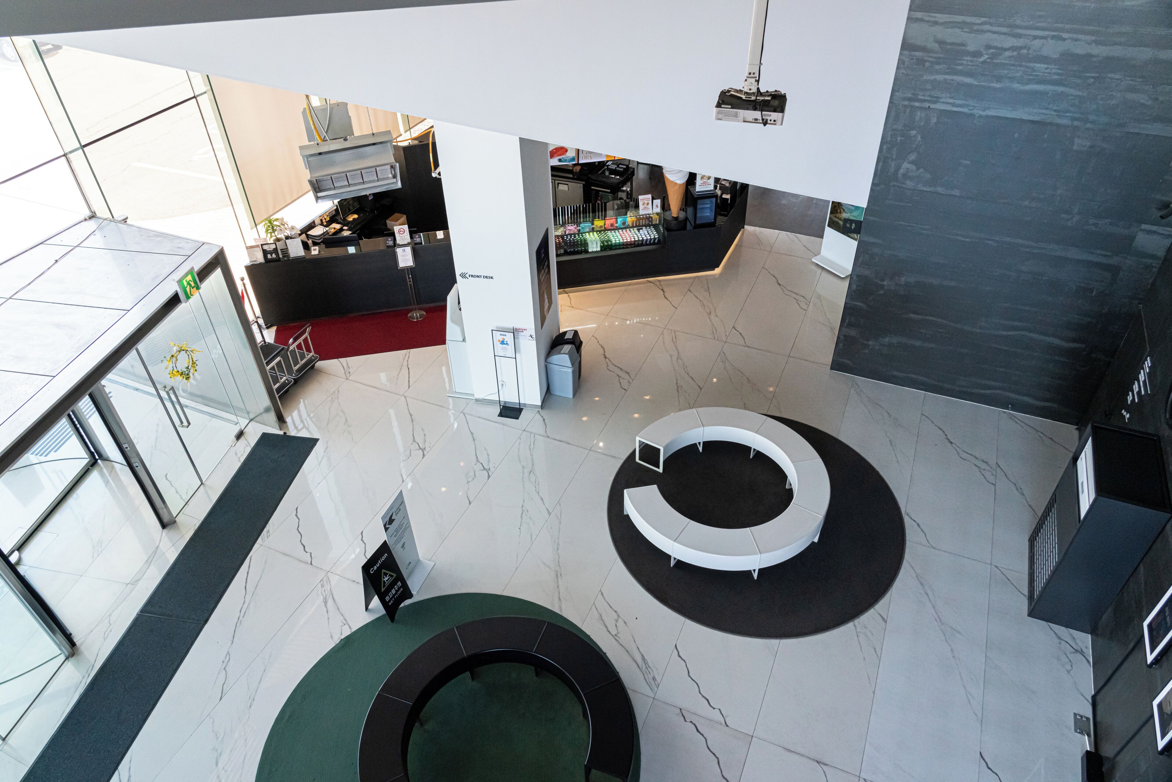 Un vestíbulo moderno con una zona de estar circular, una recepción y una máquina expendedora.