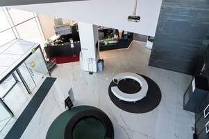 Un hall d’entrée moderne avec un espace salon circulaire, un comptoir d’accueil et un distributeur automatique.
