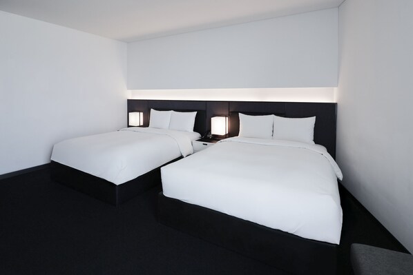 A hotel room with two beds, each with a black headboard and white bedding.