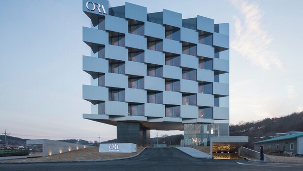 Un hotel moderno con un diseño modular único, que presenta un llamativo letrero 'ORI' en la parte superior.