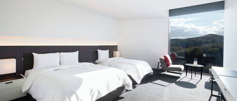 A modern hotel room with two beds, a desk, a chair, and a large window offering a view of the outdoors.