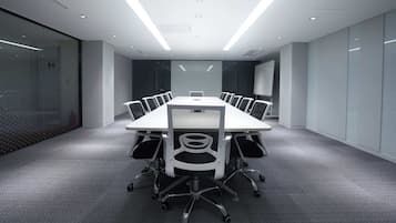 A modern conference room with a long table, chairs, and glass walls.