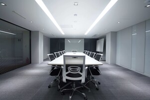 A modern conference room with a long table, chairs, and glass walls.