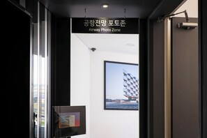 A corridor with a sign reading "Airway Photo Zone" and a framed photo of a building on the wall.