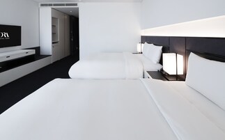 A modern hotel room with a large bed, bedside tables, a TV, and a wardrobe.