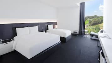 A modern hotel room with two beds, a desk, and a large window offering a view of a green landscape.